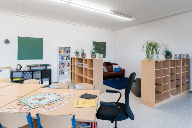 Foto: OGS Redwitz: Gruppenraum mit Tischen und Ecke mit Sofas