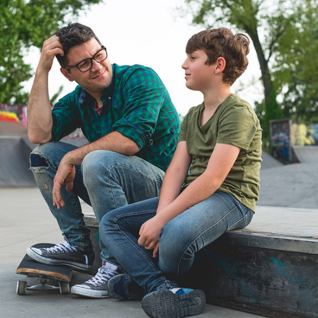 Foto: Mitarbeiter unterhält sich auf Skaterbahn mit einem Schüler